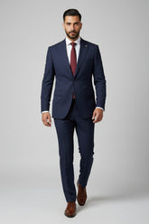Man in navy two-piece slim-fit suit with peak lapel and burgundy tie.